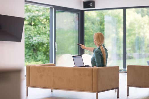 Young woman using her laptop computer in her luxury modern home, smiling