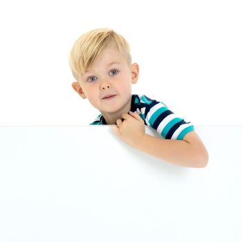 A little boy looks through an empty banner on which you can write any text. The concept of a happy childhood and advertising of children's goods. Isolated on white background.