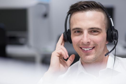 young smiling male call centre operator doing his job with a headset