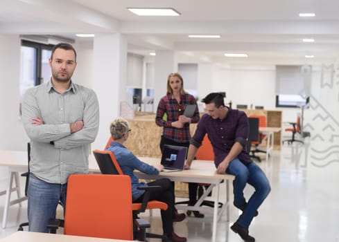 portrait of young businessman in casual clothes at modern  startup business office space,  team of people working together in background