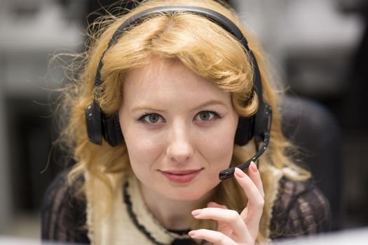 young smiling female call centre operator doing her job with a headset