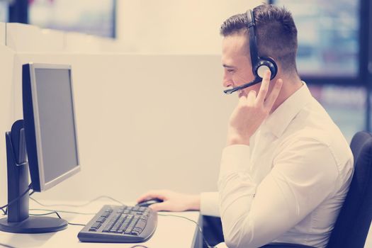 young smiling male call centre operator doing his job with a headset