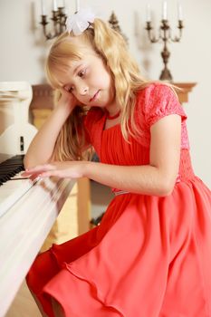 Dreaming little girl in a long orange dress,with long blonde hair braided in pigtails . Close-up