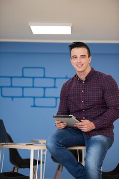 portrait of young business man in casual clothes sitting on table at  new startup office space