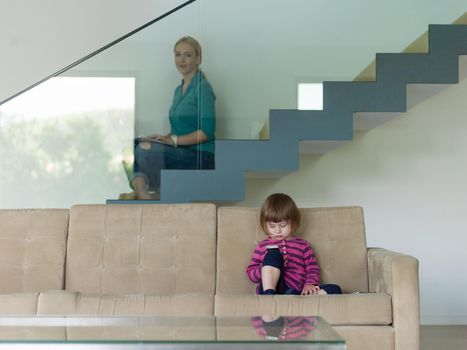 Portrait of cute little girl playing games on smartphone at home