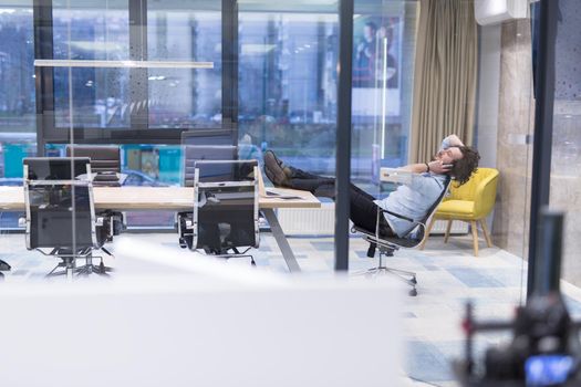 A time for relax. Young tired casual businessman relaxing at the desk in his office