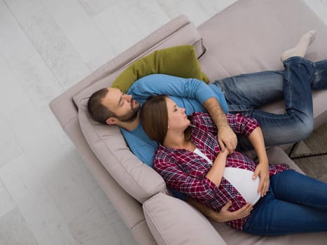 top view of happy pregnant couple relaxing on sofa couch at home