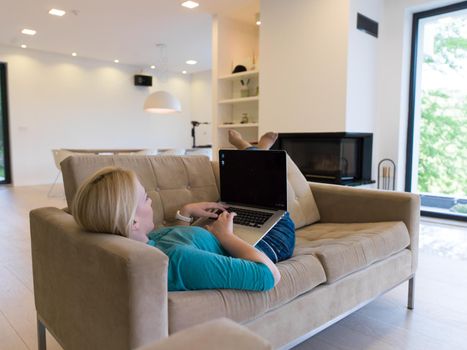 Young woman using her laptop computer in her luxury modern home, smiling