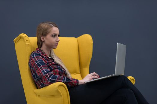 startup business, woman  working on laptop computer at modern office and sitting on creative yellow armchair