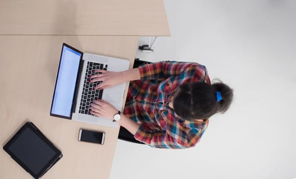 top view of young business woman working on laptop computer in modern bright startup office interior