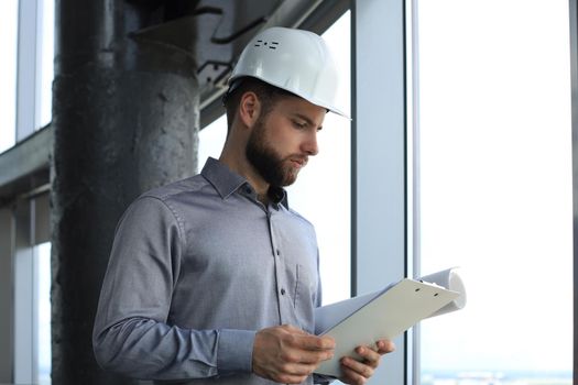 Shot of male architect wearing hardhat and inspecting new building