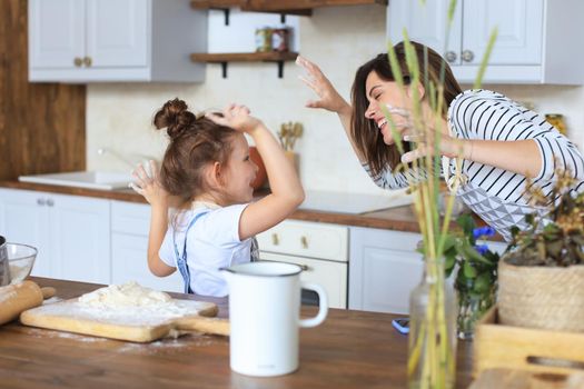 Playful little girl cooking at kitchen with her loving mother