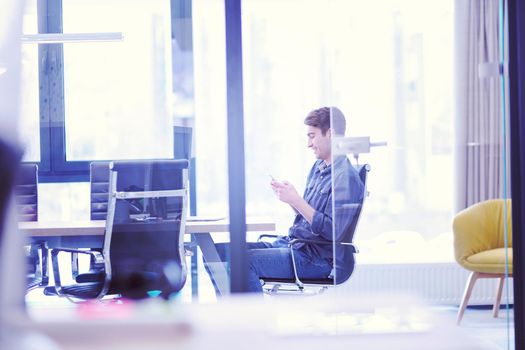 Young casual businessman using smartphone in the startup office