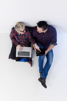 startup business and new mobile technology concept with  young couple in modern bright office interior working on laptop and tablet computer on new creative project and brainstorming, aerial top view