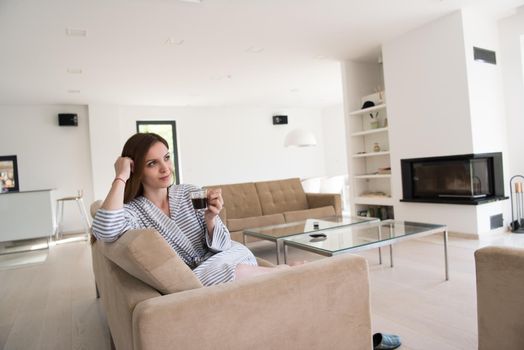 Beautifull young woman in a bathrobe enjoying morning coffee in her luxurious home villa