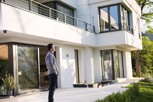 portrait of a young handsome successful man in front of his luxury home villa