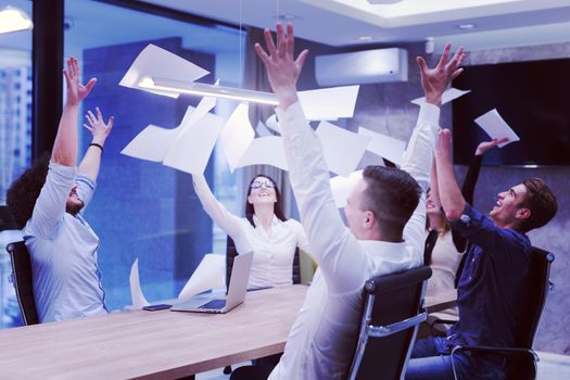 Group of young business people throwing documents and looking happy while celebrating success at their working places in startup office