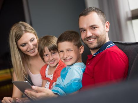 Happy Young Family Playing Together with tablet at home sitting on the sofa