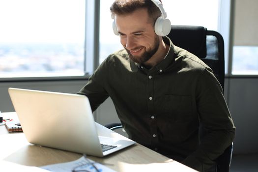 Young modern business man working using laptop while sitting in the office