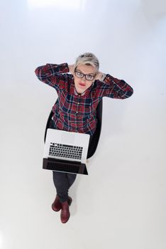 top view of young business woman working on laptop computer in modern bright startup office interior, sitting on floor