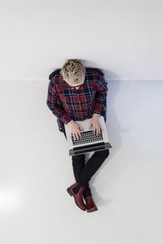 top view of young business woman working on laptop computer in modern bright startup office interior, sitting on floor