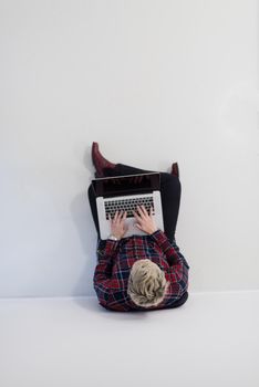 top view of young business woman working on laptop computer in modern bright startup office interior, sitting on floor