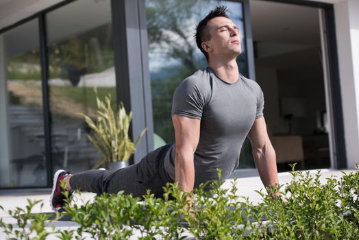 young handsome man doing morning yoga exercises in front of his luxury home villa