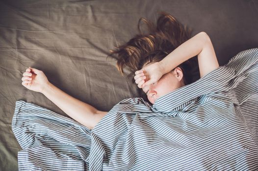 Beautiful young woman lying down in bed and sleeping, top view. Do not get enough sleep concept.