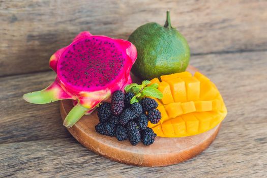 Sliced dragon fruit and mango on an old wooden background.