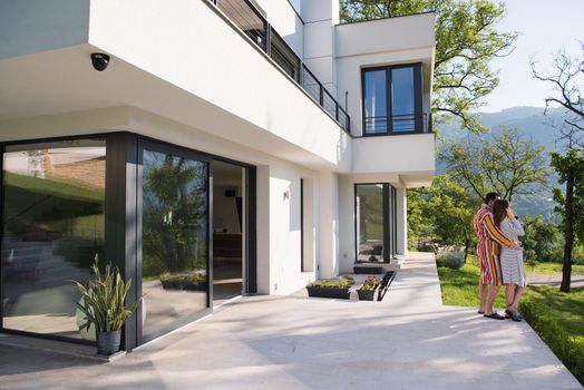 Young beautiful couple in bathrobes are enjoying morning coffee in front of their luxury home villa