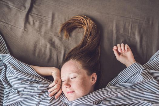 Beautiful young woman lying down in bed and sleeping, top view. Do not get enough sleep concept.