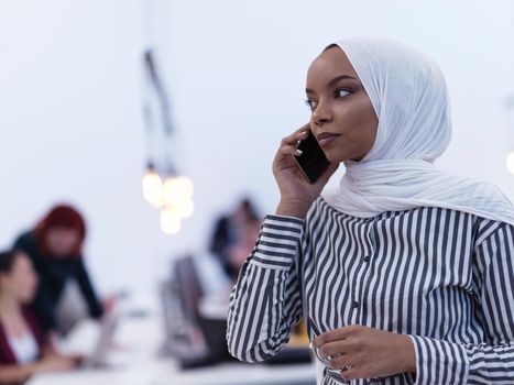 african muslim businesswoman using smart phone  wearing hijab at creative modern startup coworking open space office