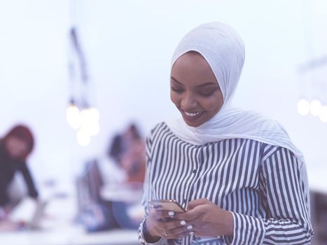 african muslim businesswoman using smart phone wearing hijab at creative modern startup coworking open space office