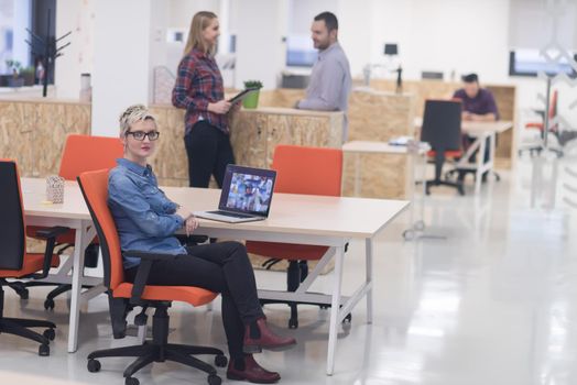 portrait of young business woman at modern startup office interior, team in meeting in background