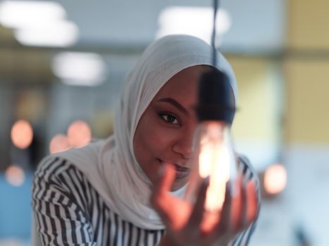 african american muslim businesswoman holding hands around light bulb concept of smart saving energy and busines creative solutions