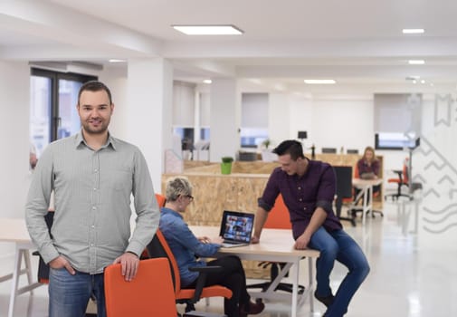 portrait of young businessman in casual clothes at modern  startup business office space,  team of people working together in background