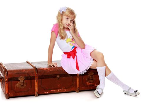Beautiful little girl in a pink short skirt and white socks sitting on the old road suitcase-Isolated on white background