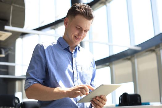 Young businessman using his tablet in the office