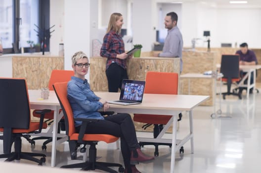 portrait of young business woman at modern startup office interior, team in meeting in background