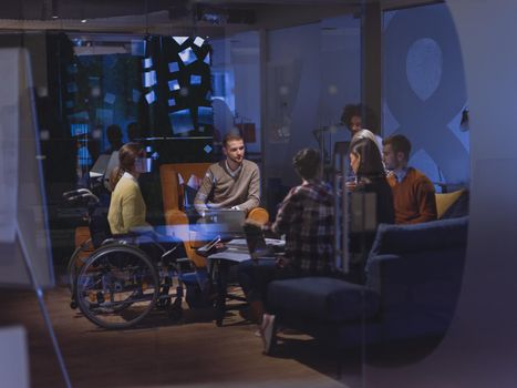 Disabled businesswoman in a wheelchair having a meeting with the diverse business people team at modern startup open space office 