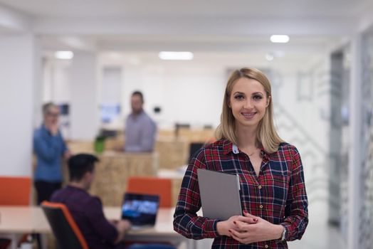 portrait of young business woman at modern startup office interior, team in meeting in background