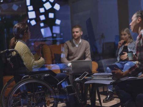 Disabled businesswoman in a wheelchair having a meeting with the diverse business people team at modern startup open space office 