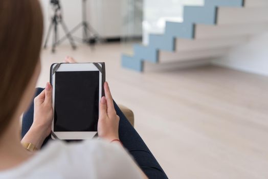 young happy woman sitting on sofa with tablet computer at luxury home