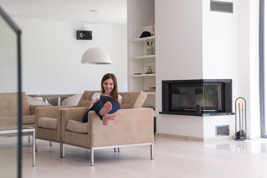 young happy woman sitting on sofa with tablet computer at luxury home