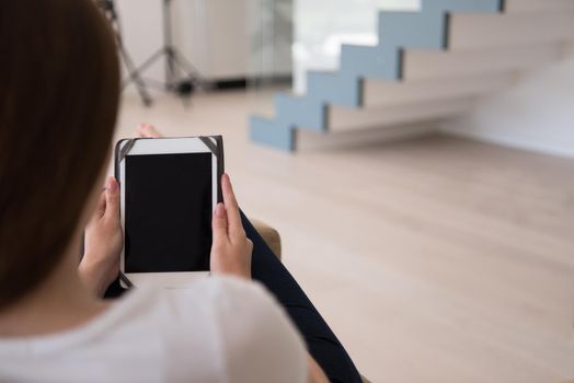 young happy woman sitting on sofa with tablet computer at luxury home