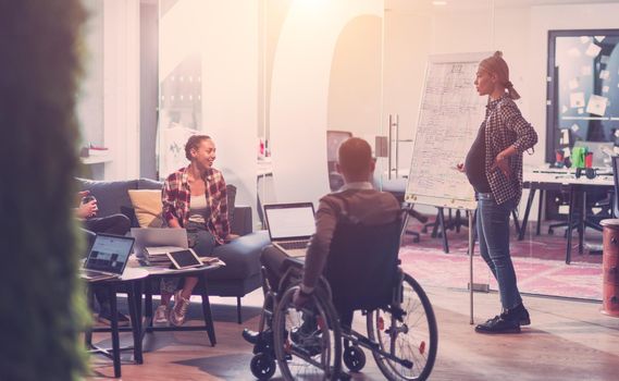 Pregnant Businesswoman Leads Creative Meeting Of Diverse Business Team In Modern Coworking Open Space Office, Disabled coworker in wheelchair attending training 