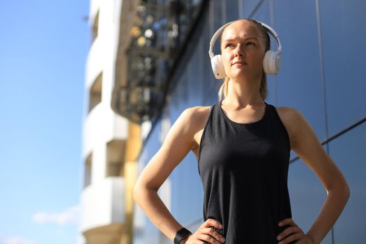 Beautiful woman in sports clothing looking at camera while exercising outdoors