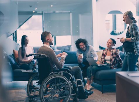 Pregnant Businesswoman Leads Creative Meeting Of Diverse Business Team In Modern Coworking Open Space Office, Disabled coworker in wheelchair attending training 