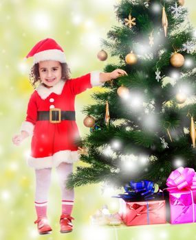 Smiling curly-haired little girl, dressed as Santa Claus decorates a Christmas tree toys.On a green background with white snowflakes.