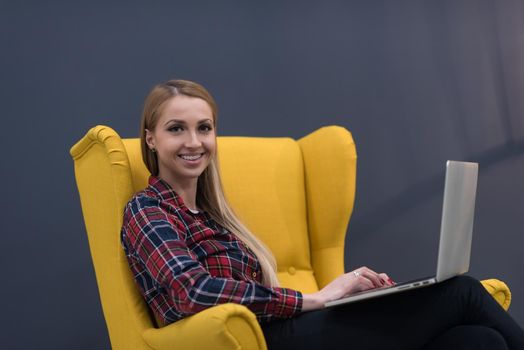 startup business, woman  working on laptop computer at modern office and sitting on creative yellow armchair